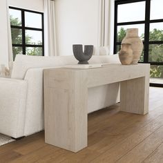 a white couch sitting next to a table on top of a hard wood floor in front of large windows