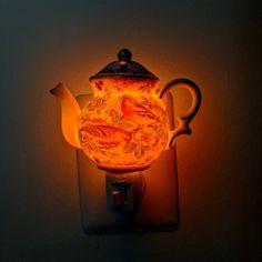 a teapot shaped light is lit up on the wall next to a lamp shade