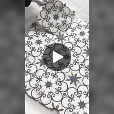 the video is showing how to make an intricate tile design with white and black tiles