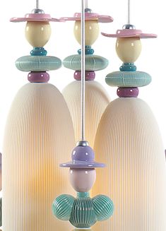 a group of vases with hats on top of them hanging from strings in front of a white background