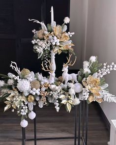 a white and gold christmas centerpiece with deer, pineconis, berries, flowers