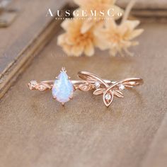 two opal rings sitting on top of a wooden table next to a bouquet of flowers