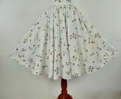 On a white cotton background, this wonderful novelty cotton summer circle skirt is chock full of black buzzing bees pollinating tomato red mid century stylized flowers. The waist buttoned is 24 1/2 inches, It closes in back with a metal zipper and carved shell button. It is not lined. LABEL: none CONDITION: very good plus presents beautifullyage and wear have resulted in very mild fading of fabric. When purchased, the skirt had what looked like coffee stains on front lower half , which improved Retro White Skirt For Summer, White Cotton Skirt For Garden Party, White Full Skirt For Garden Party, Vintage White Full Skirt, Retro Cotton Summer Skirt, Cotton Fitted Skirt For Garden Party, Vintage White Gathered Skirt, Vintage White Floral Print Skirt, White Vintage Gathered Skirt