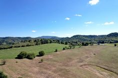 an aerial view of a field with trees and mountains in the background