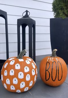 two pumpkins with ghost faces and the words boo on them are sitting in front of black chairs