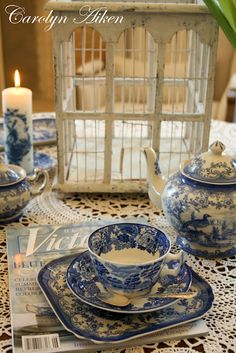 a blue and white tea set sitting on top of a table next to a candle