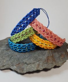 four crocheted bracelets sitting on top of a rock