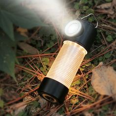 a flashlight that is sitting on the ground in the grass with some leaves around it