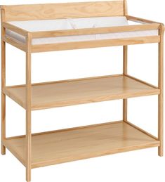 a wooden baby crib with white sheets on it's sides and bottom shelf