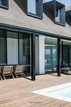 an outside view of a house with wooden decking and sliding glass doors leading to the pool