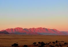 the sun is setting over mountains in the desert