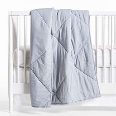 a white crib with a blue quilt on it