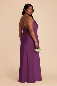 a woman in a long purple dress is looking back at the camera with her hand on her hip