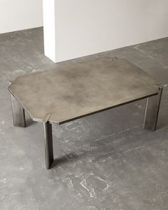 a concrete coffee table sitting on top of a cement floor next to a white wall