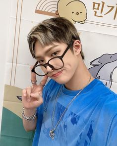 a young man wearing glasses making the peace sign with his hand while standing in front of a dolphin wall