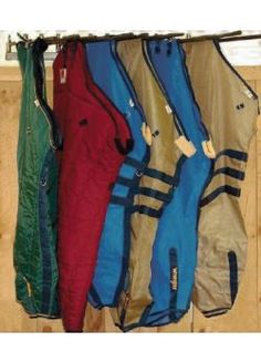 four snowboard jackets hanging on a rack in front of a window with wood flooring