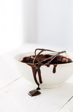 a white bowl filled with chocolate sauce on top of a wooden table