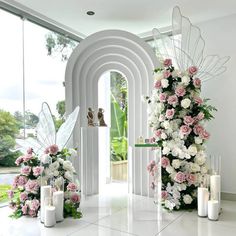 flowers and candles are arranged on the floor in front of an arch that leads into a garden