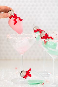 someone is decorating two martini glasses with candy