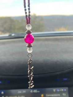 a car dashboard with a pink beaded necklace hanging from it's center console