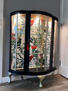 a display case in the corner of a room with flowers and birds on it's glass doors