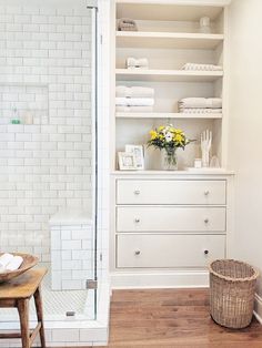 a white bathroom with open shelving and wooden flooring