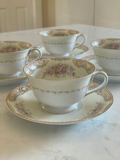 four tea cups and saucers sitting on a table