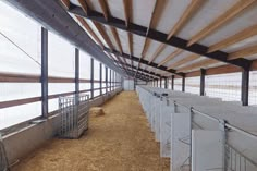 the inside of a barn with hay and metal railings on both sides of the stalls