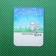 a small card with an image of two dogs sitting on the grass and stars in the sky