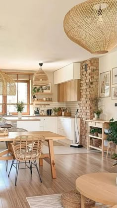 an open kitchen and dining room with wood floors, white walls and wooden table surrounded by wicker chairs