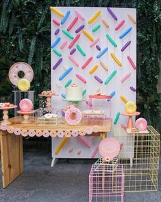 a table topped with lots of donuts next to a wall covered in sprinkles