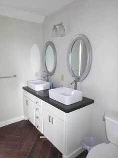 a bathroom with two sinks, mirrors and a toilet in the corner next to each other