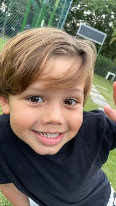 a young boy is smiling and holding his hand up