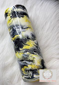 a black, yellow and white marbled canister on a fur surface with the lid open