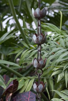 a tall metal plant with lots of leaves in the background