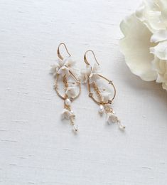 Our Irena teardrop Hoop Floral earrings for Bride are designed to be show stopping dangle hoops that will have everyone asking "where did you get those?!" Crafted with off white flower clusters & dangling freshwater pearls and white opal Austrian crystal beads, these earrings are perfect for casual or formal wear. - Handcrafted with genuine Austrian crystals- Created in my studio in PA- White opal crystals- Freshwater pearls- Polymer clay flowers- Yellow gold finish.- Earrings measure 3.25 inches x 1 inch- Handcrafted in the US.- Nickel free and hypoallergenic- PLEASE ALLOW APPROX 10 BUSINESS DAYS FOR COMPLETION BEFORE SHIPPING.This is an original design by © Treasures by Agnes Delicate White Hoop Earrings With Pearl Drop, White Drop Hoop Earrings For Pierced Ears, Delicate White Teardrop Flower Earrings, White Drop Hoop Earrings, White Drop Chandelier Earrings, White Teardrop Hoop Earrings For Wedding, White Teardrop Jewelry With Flower Charm, Delicate White Teardrop Earrings, Handmade White Dangle Cluster Earrings