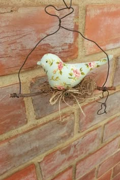 a white bird sitting on top of a nest in front of a brick wall,