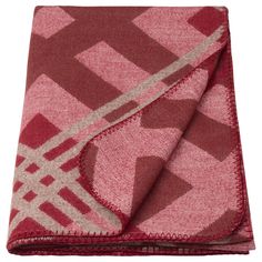 a pink and red blanket folded on top of a white surface with an abstract design