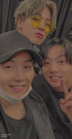 three young men posing for the camera with one wearing a bandana and two pointing fingers at the camera