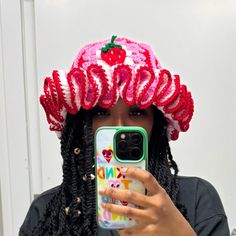 a woman taking a selfie with her cell phone wearing a strawberry hat on top of her head