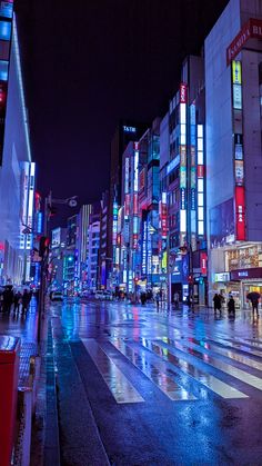 a city street at night with people crossing the street