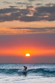 surfers are surfing at sunset and the sun sets over the ocean with their surfboards