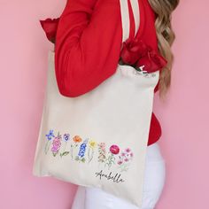 a woman holding a tote bag with flowers on it