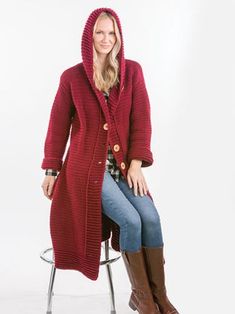 a woman is sitting on a chair wearing a red cardigan sweater and brown boots