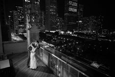 a bride and groom kissing on the balcony of their hotel room in chicago at night