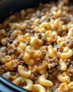 a crock pot filled with macaroni and cheese on top of ground beef