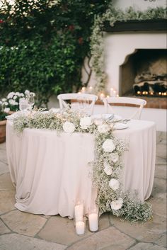 a table with flowers and candles on it in front of a fire place at a wedding