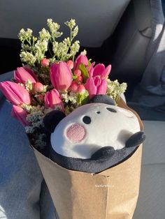 a stuffed animal in a paper bag with flowers