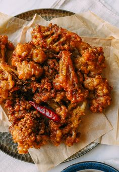 a plate full of fried food on top of a white table cloth next to a fork and knife