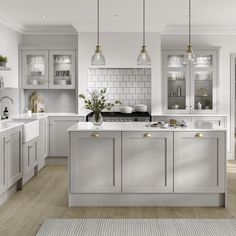 a white kitchen with lots of counter space and lights hanging from the ceiling over the island